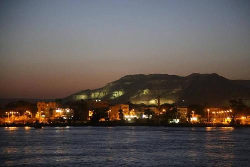 a city at night with a mountain in the background at Cleopatra Hotel Luxor in Luxor
