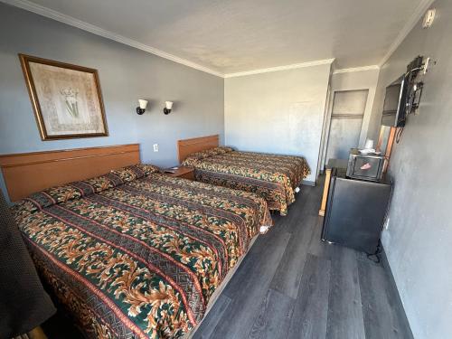 a hotel room with two beds and a tv at Harbor Inn in Harbor City