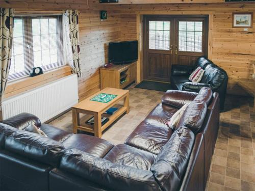 a living room with leather couches and a television at No 6 Lake View Lodges - 28283 in Old Leake