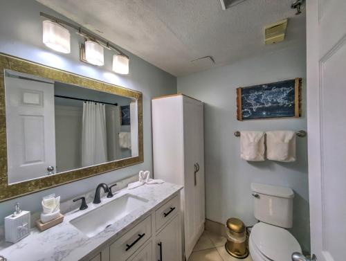 a bathroom with a sink and a toilet and a mirror at Pirates Bay B114 in Fort Walton Beach