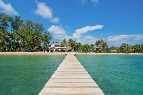 a wooden pathway leading to a beach with a house at Makathanee Resort in Ko Mak