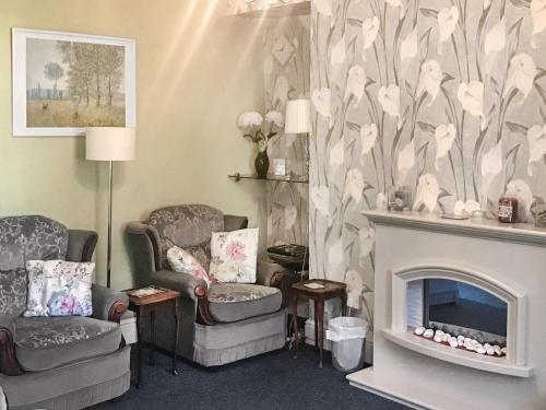 a living room with two chairs and a fireplace at Hazeldene in Bishopston