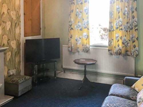 a living room with a tv and a table at Hazeldene in Bishopston
