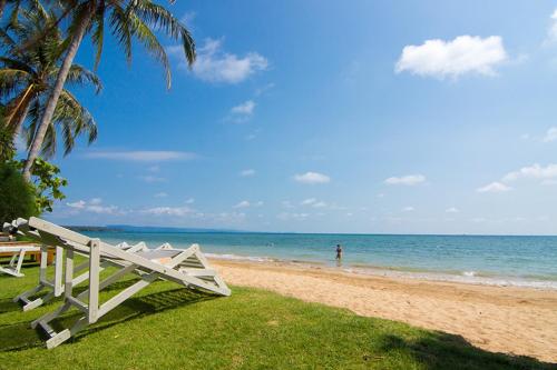 a beach with a white bench and the ocean at Makathanee Resort in Ko Mak