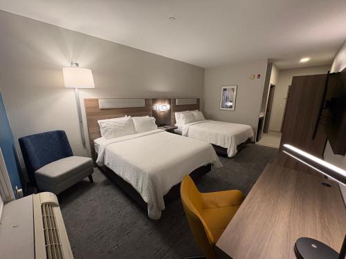 a hotel room with two beds and a chair at Holiday Inn Express Hotel & Suites Lafayette by IHG in Lafayette