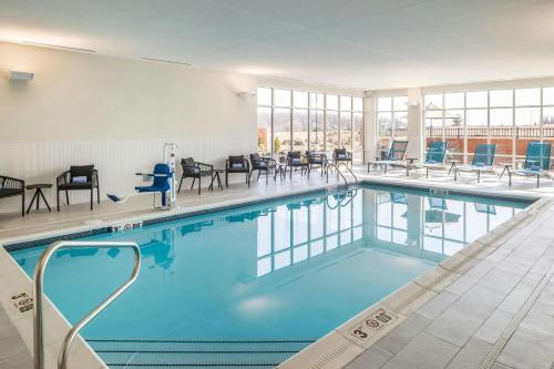 a swimming pool with chairs and tables in a building at SpringHill Suites by Marriott Canfield in Canfield