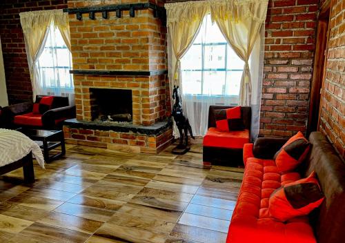 salon z ceglanym kominkiem i czerwonymi kanapami w obiekcie Finca San Pedro w mieście Hacienda Santa María