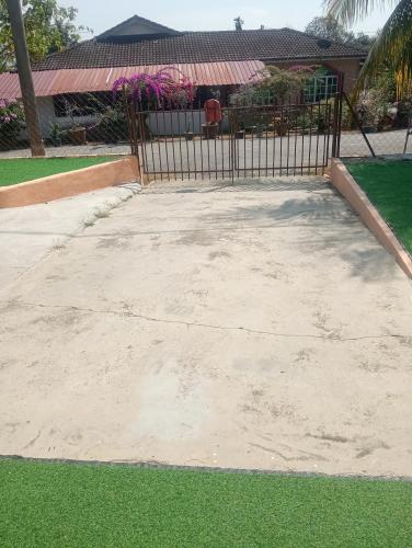 a concrete driveway with a fence and green grass at Santai DPermai Homestay in Selama