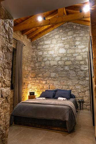a bedroom with a stone wall with a bed at Philoxenia Stone Suites in Choulou