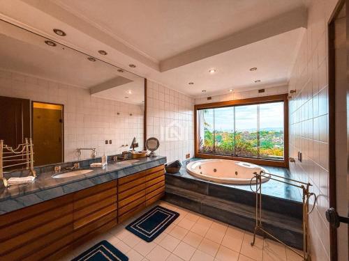 a large bathroom with a tub and a large window at Casa Flora Garden & Pool in Carapicuíba