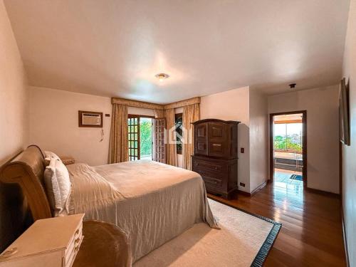 a bedroom with a bed and a dresser and a television at Casa Flora Garden & Pool in Carapicuíba