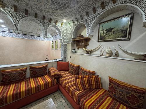 a room with three couches and a painting on the wall at Riad Razoli Sidi Fateh in Rabat