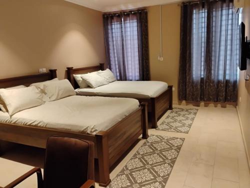 a bedroom with two beds and a chair in it at Chateau de Mankosah in Accra