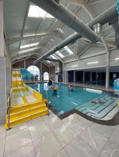a large swimming pool with a pool slide in a building at Lily's caravan in Meliden