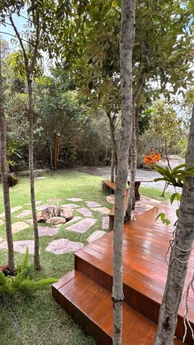 a wooden deck in the middle of a garden with trees at Casa.dovale3 in Caeté-Açu