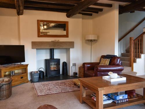 a living room with a fireplace and a couch and a table at Barn End in Watermillock