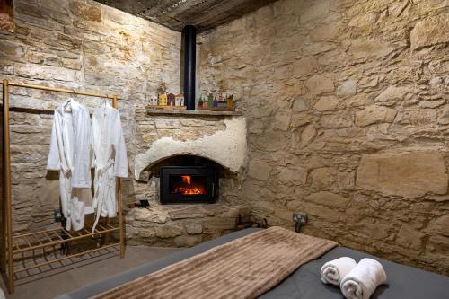a stone walled room with a fireplace and a bed at Philoxenia Stone Suites in Choulou