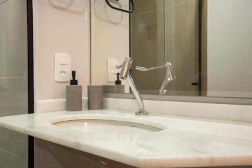 a bathroom with a white sink and a mirror at Essential 2U in São Paulo