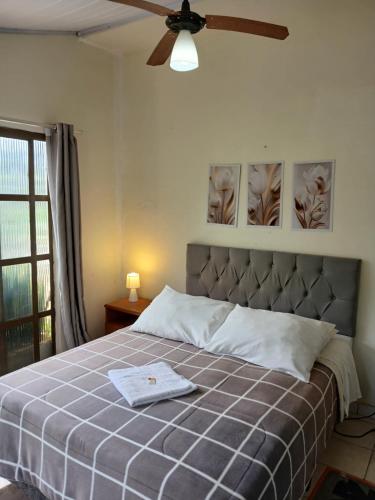 a bedroom with a bed with a ceiling fan at Pousada Recanto Alegre in Campestre