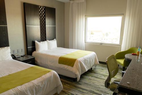 a hotel room with two beds and a window at Hotel Mirra San Luis in San Luis Río Colorado