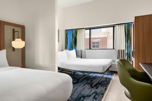 a room with two beds and a chair and a window at Fairfield by Marriott Inn & Suites Charleston Downtown in Charleston