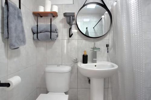 a bathroom with a toilet and a sink and a mirror at Bougainvillea House in Ponta do Pargo
