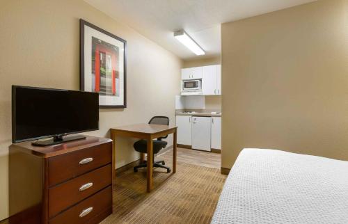 a hotel room with a bed and a desk with a television at Extended Stay America Suites - Albuquerque - Airport in Albuquerque