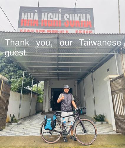 a man standing with a bike in front of a building at Nhà Nghỉ Sukha in Ba Vì