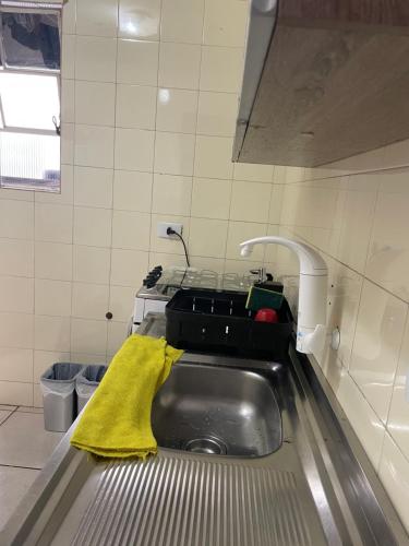 a kitchen with a stainless steel sink with a yellow towel at Quarto Privado em Apto Bigorrilho in Curitiba