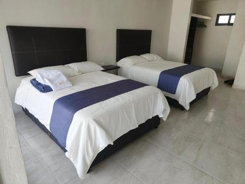 two beds in a hotel room with at Oasis Hotel Jojutla in Vallespin