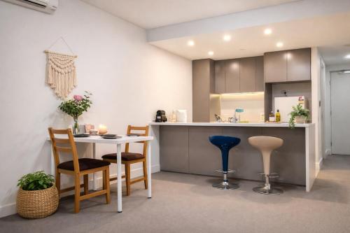 a kitchen with a table and chairs and a counter at Skyline Comfort - Sydney Olympic Park in Sydney