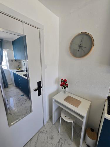 a small white table with a clock on a wall at Blue Studio - Cozinha Privativa - Eficacia Living Abrantes in Abrantes
