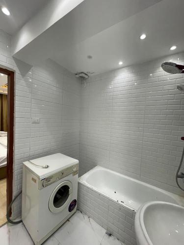 a white bathroom with a washing machine and a tub at استديوهات3 Hs Hotels استديو مخدوم in Cairo