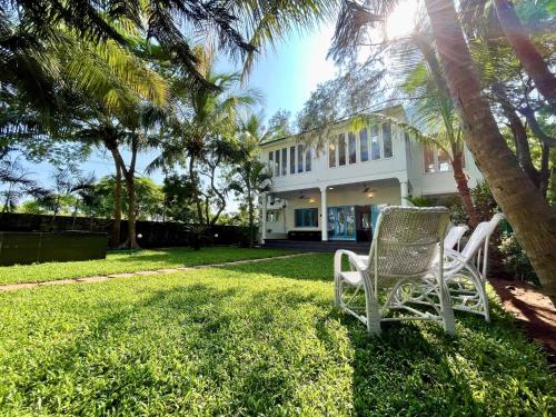 two chairs sitting in the grass in front of a house at La Maison Bougainvillea in Mahabalipuram