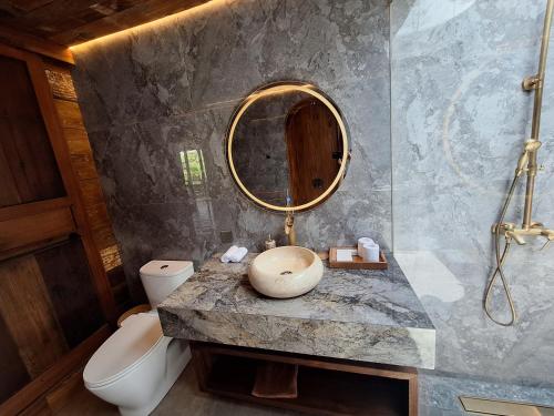 a bathroom with a sink and a toilet and a mirror at Uma Cabins by Uma Experience in Penginyahan