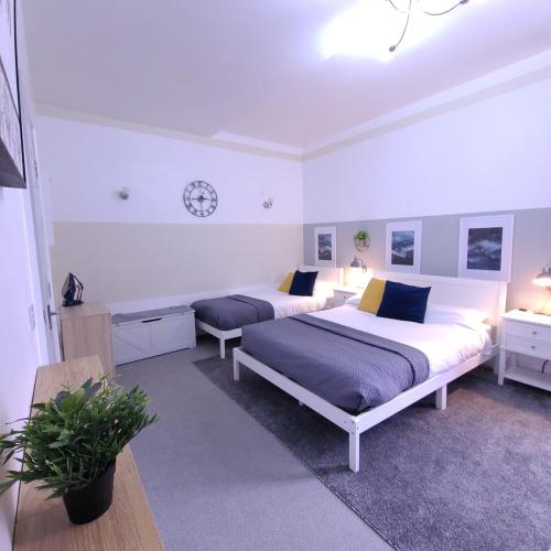 a bedroom with two beds and a clock on the wall at InstaLet Apartments I Wigan Central I Free Parking in Wigan