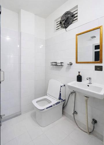 a white bathroom with a toilet and a sink at Tamasha Udaipur in Udaipur