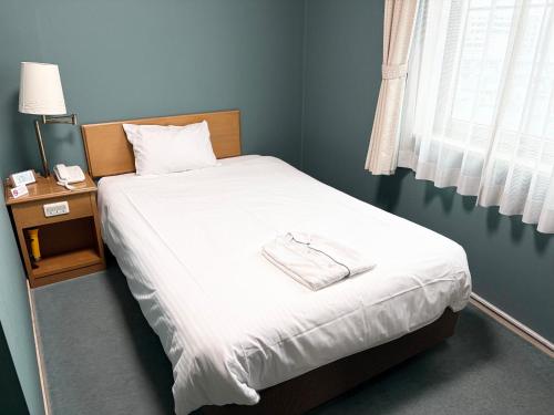 a bedroom with a bed with white sheets and a lamp at 湘南鎌倉クリスタルホテル in Kugenuma