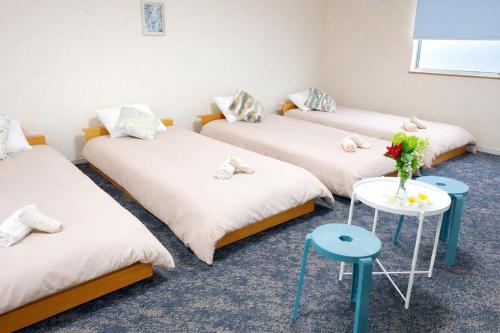four beds in a room with flowers on a table at MY HOUSE たいみんぐ kuwana 長島15分 名古屋20分 桑名駅徒歩3分 in Kuwana