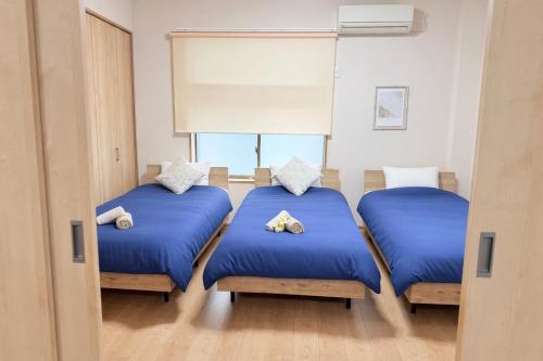 three beds in a room with blue sheets and pillows at MY HOUSE たいみんぐ kuwana 長島15分 名古屋20分 桑名駅徒歩3分 in Kuwana