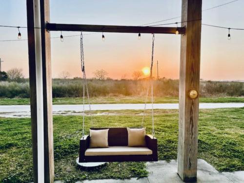 a couch on a porch with the sunset in the background at Pelican Pointe Home for 10 in Bolivar Peninsula