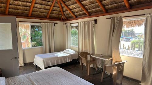 a bedroom with a bed and a table and two windows at Bungalows Las Palmas Cabo Pulmo in Cabo Pulmo
