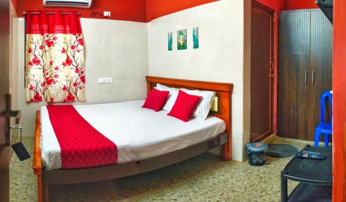 a bedroom with a bed with red pillows at Hotel Jyothi Kumar Royal ac rooms in Srikalahasti