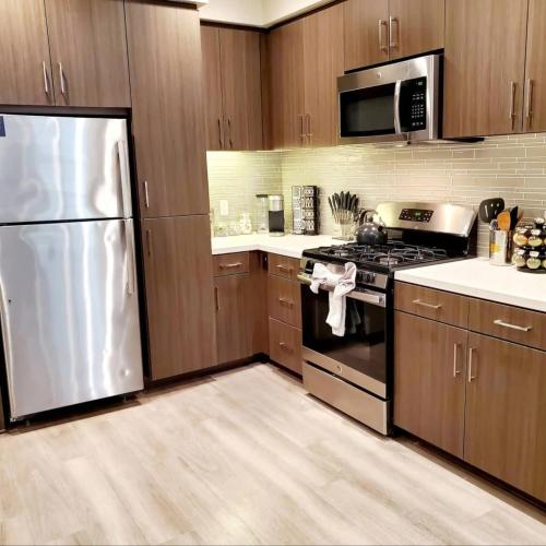 a kitchen with stainless steel appliances and wooden cabinets at Spacious 2 bed 2 bath, Pool, Hottub, Wifi, 24 hr Fitness, Parking in Los Angeles