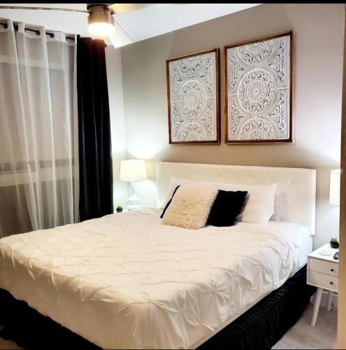 a bedroom with a white bed with two pictures on the wall at Spacious 2 bed 2 bath, Pool, Hottub, Wifi, 24 hr Fitness, Parking in Los Angeles