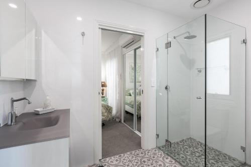 a white bathroom with a shower and a sink at Waves at Warilla in Barrack Point