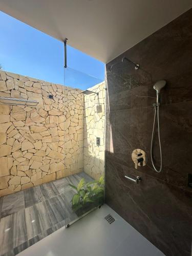 a bathroom with a shower with a stone wall at Windy Beach House 1 in Ấp Bình Tú