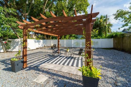 a wooden pergola with a table and chairs under it at Cozy bungalow with Luxe Yard, Firepit, Pergola Area in Tampa