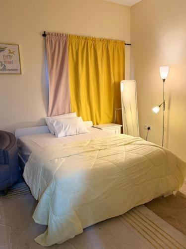 a bedroom with a large bed with a yellow curtain at Studio appartment well Furnished in Ajman