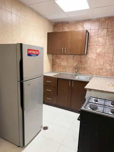 a kitchen with a stainless steel refrigerator and wooden cabinets at Studio appartment well Furnished in Ajman